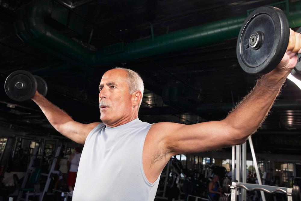 A man is lifting weights at a gym. 