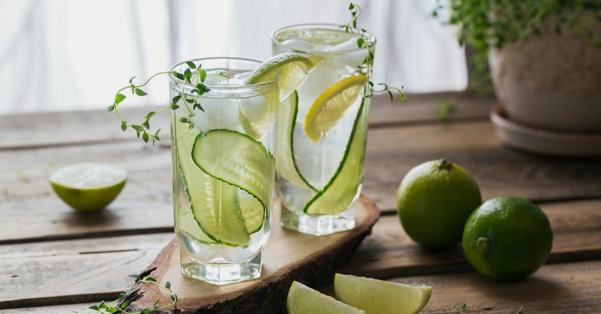 Two glasses of refreshing looking iced water with cucumber, thyme, and lemon 