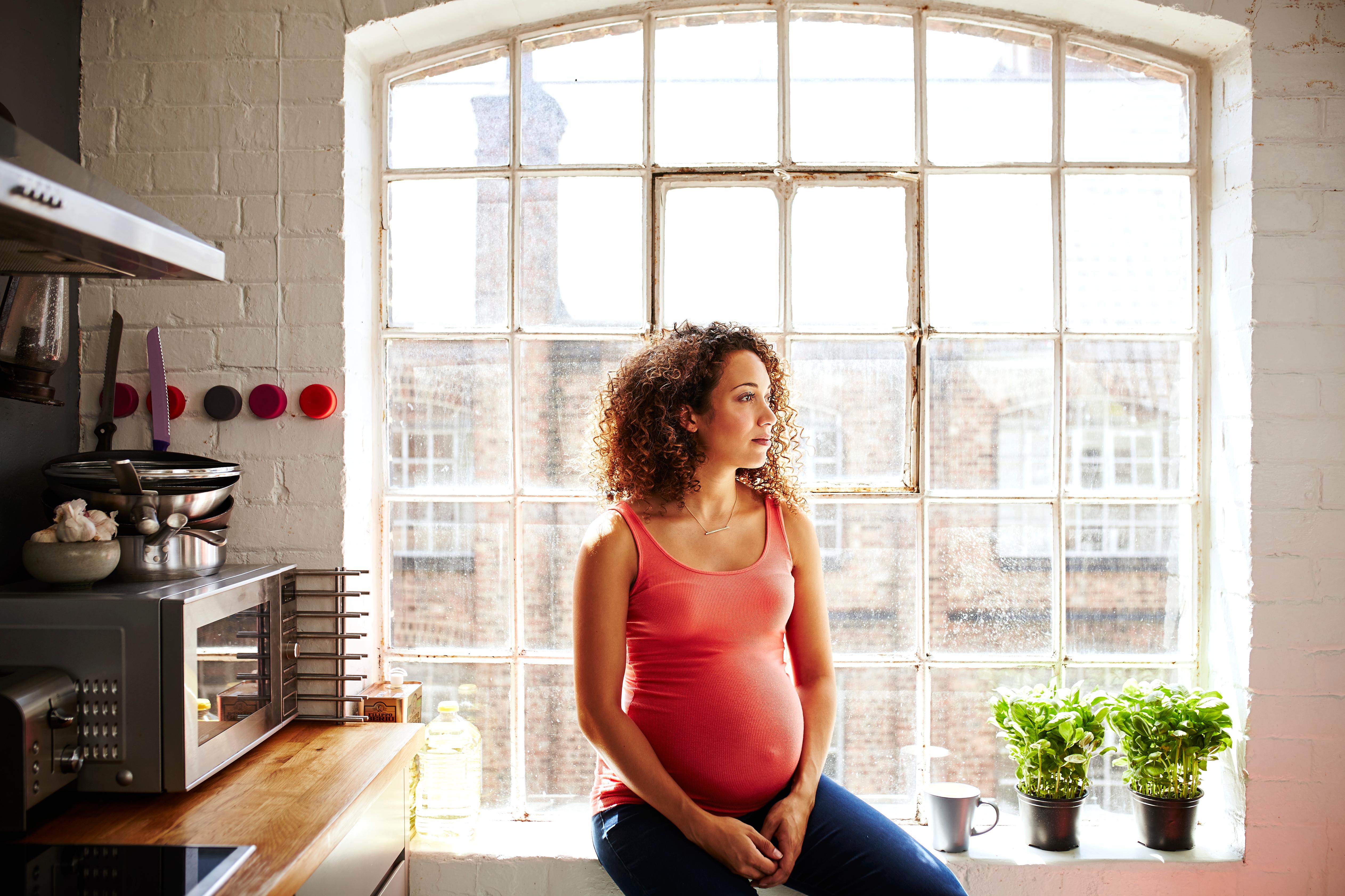 Pregnant woman sitting in the kitchen.