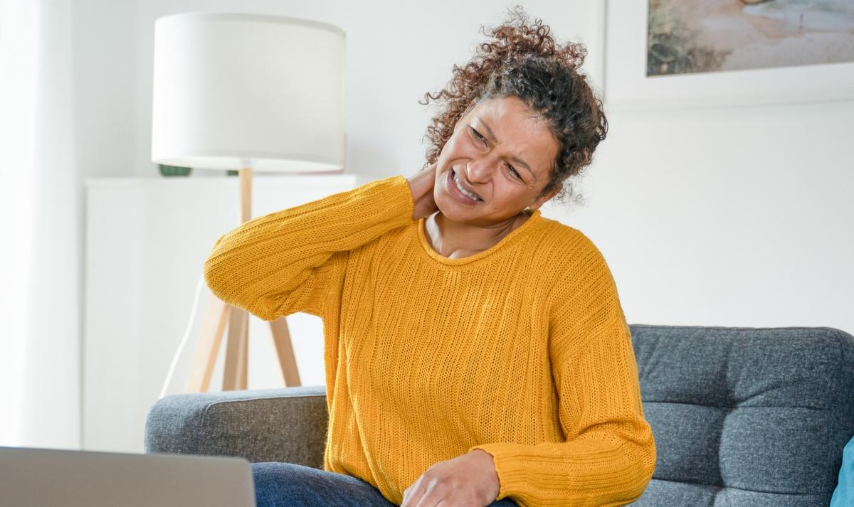 woman in yellow sweater rubbing neck