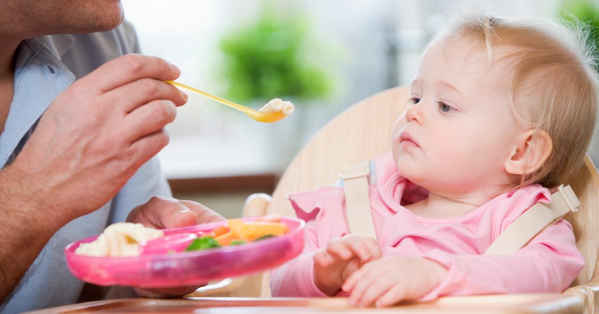 Parent feeds baby in a high chair