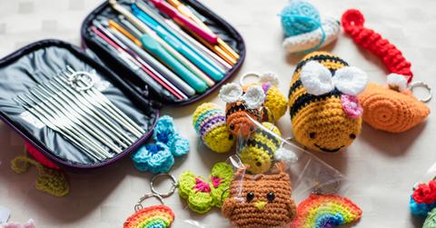 A kit full of different crochet hooks and tools surrounded by various crocheted figures like bees, rainbows, and butterflies.