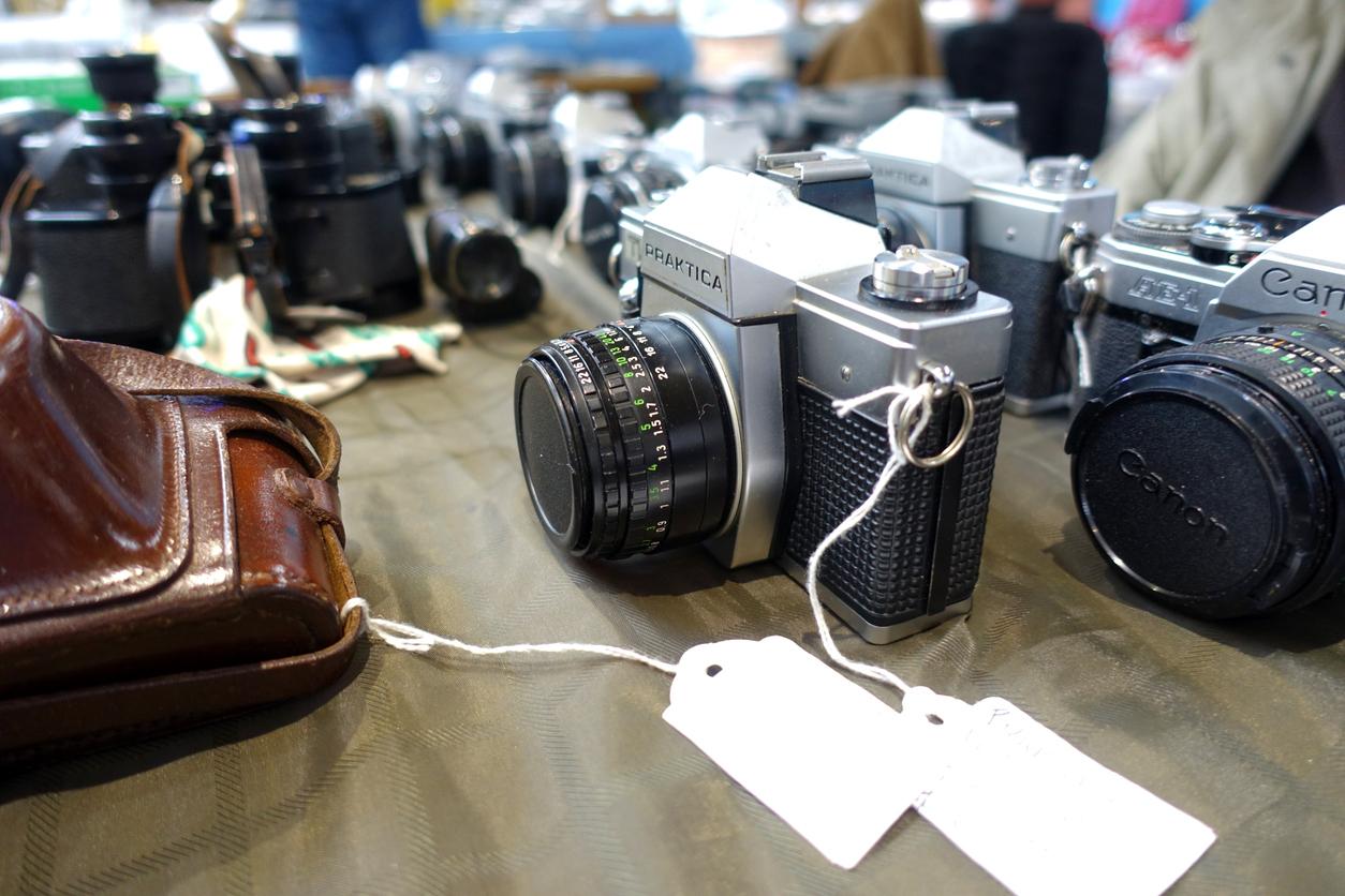 An old black and gray Praktica camera for sale at a secondhand store.