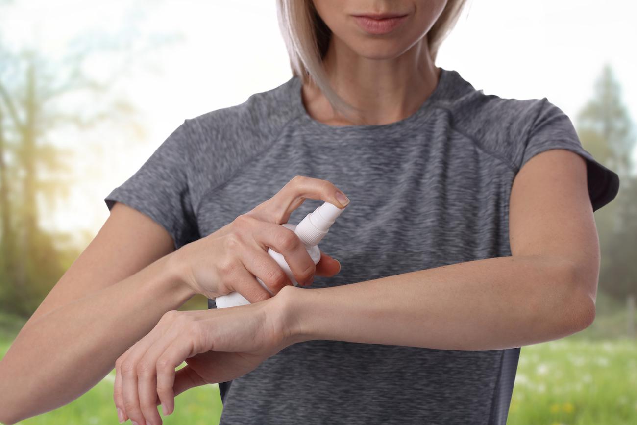 Woman sprays her wrist with bug spray