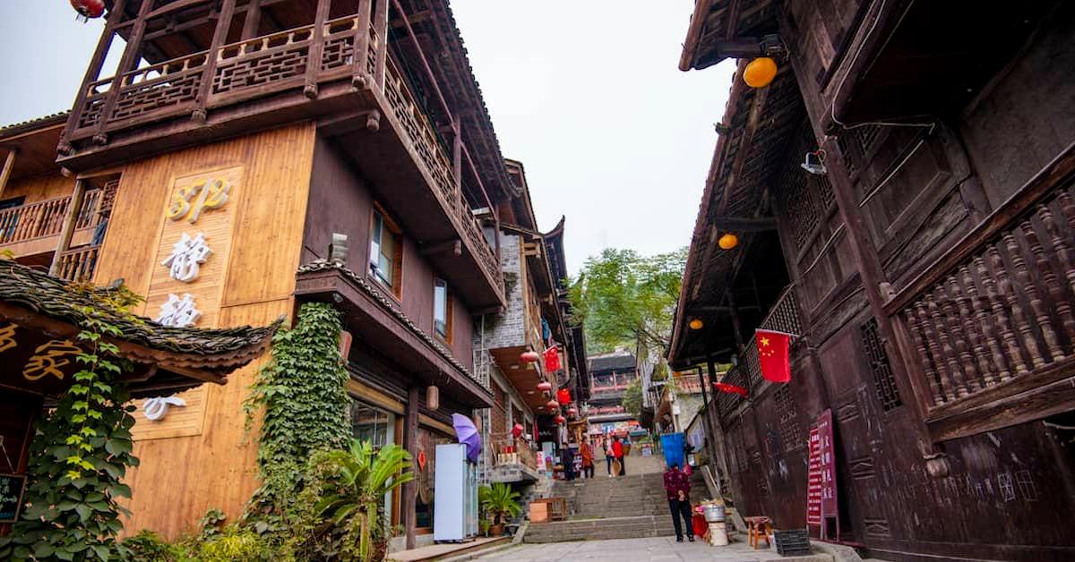 Low-angle view of a pedestrian staircase leading up through ornate wooden buildings in Furong Town.