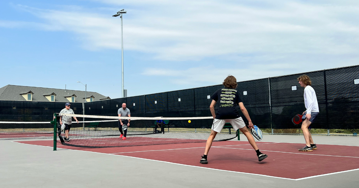 Pickleball players stand on the court