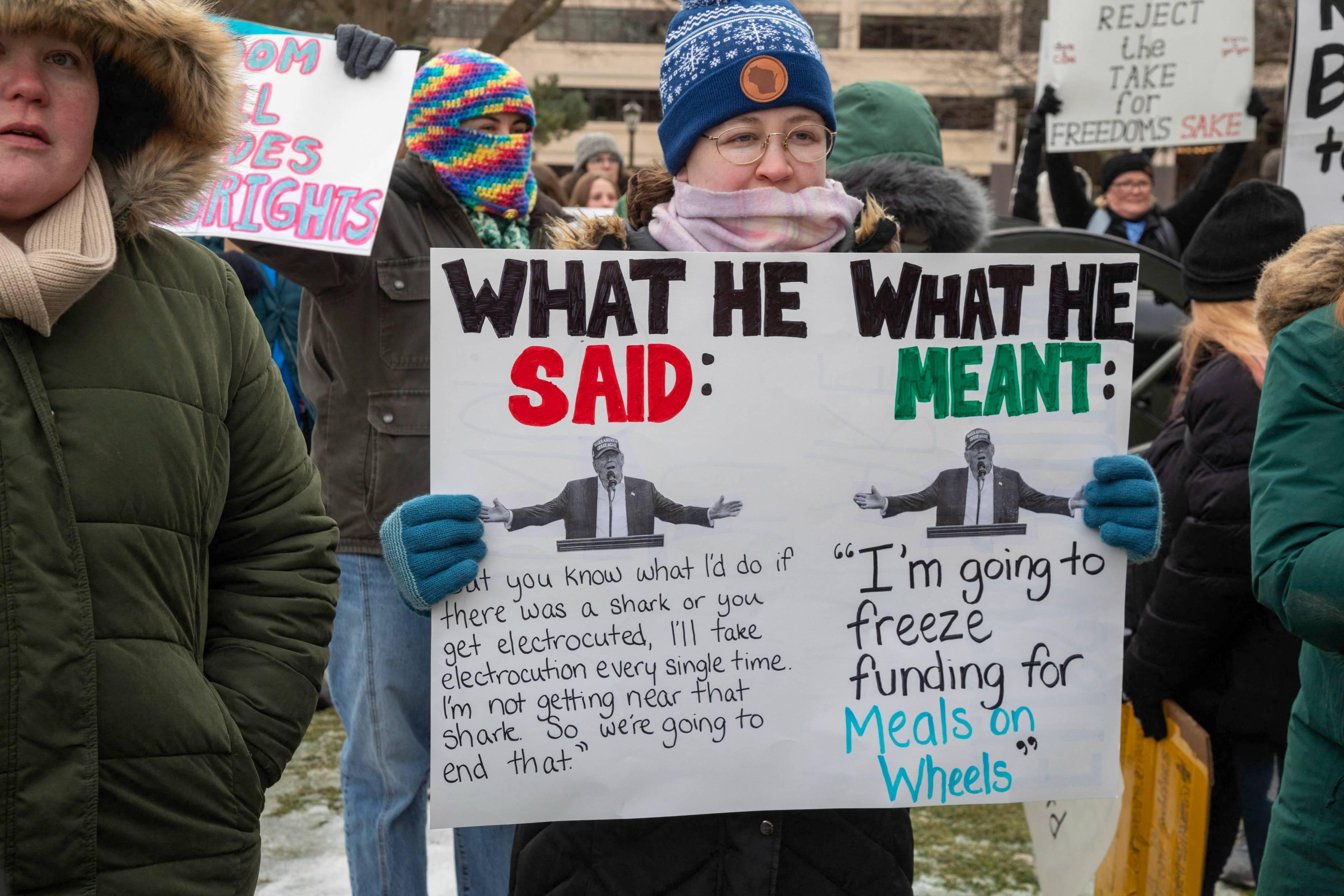 A protestor at the Michigan state capitol holds a sign claiming President Trump will cut funding for Meals on Wheels.
