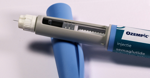 An Ozempic injectable lays on its side with the needle exposed