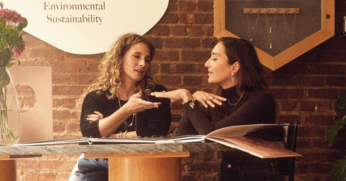 Two women wearing jewelry sitting at a table.