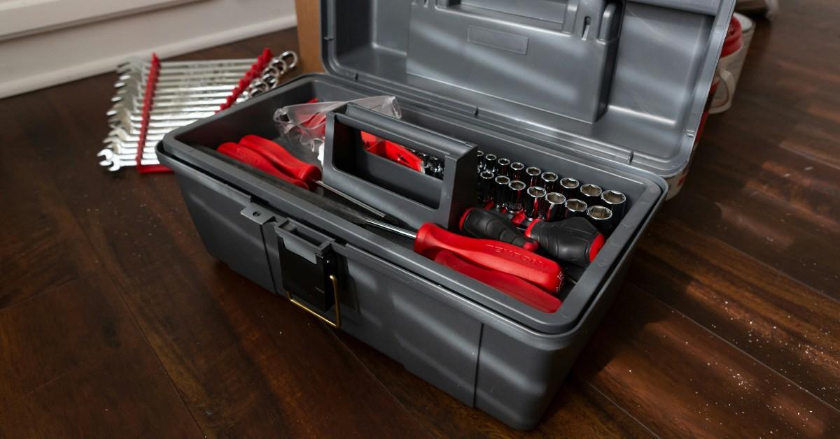 A gray tool box sits open showing off some red and black tools