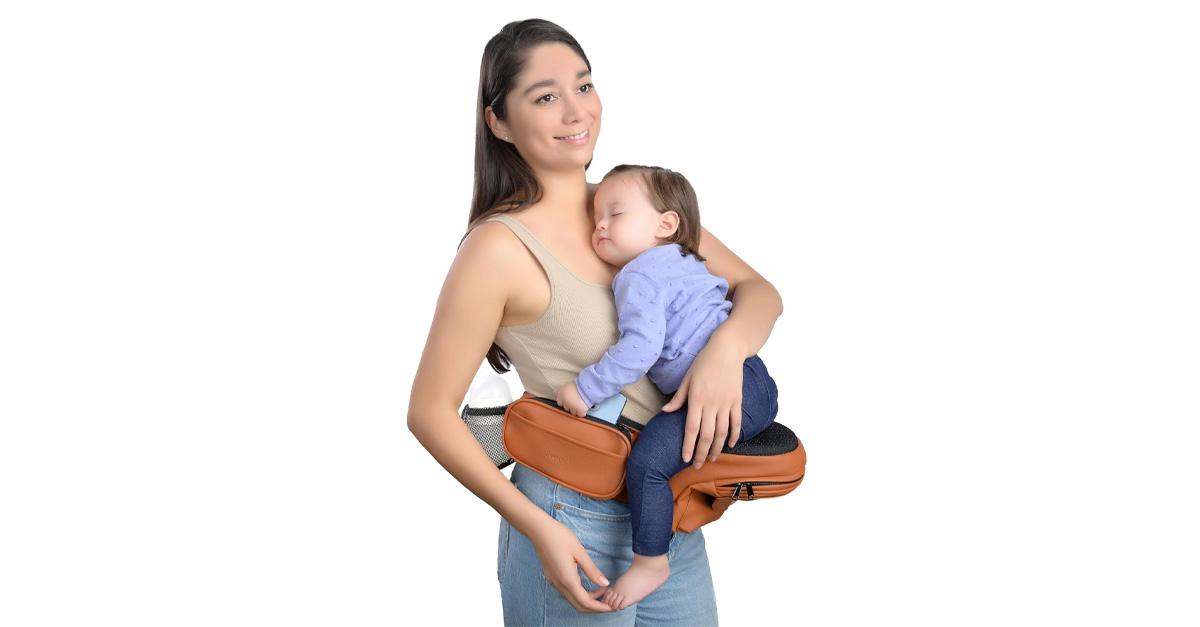 Smiling mom carrying baby in vegan leather hip seat baby carrier.