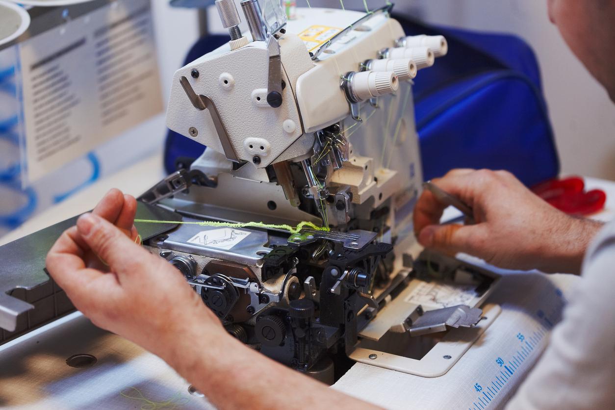 Close up view of a sewing machine being repaired by someone.