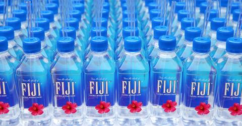 Numerous Fiji water bottles with straws lined up on a table