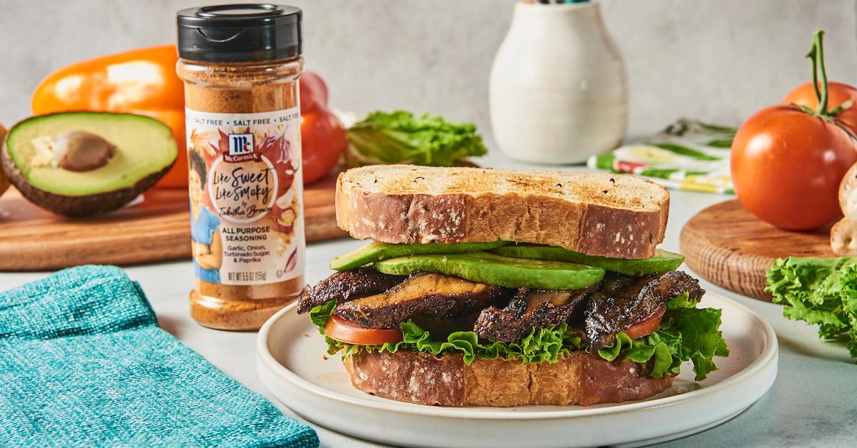 A bottle of Like Sweet Like Smoky All Purpose Seasoning sits next to a sandwich.