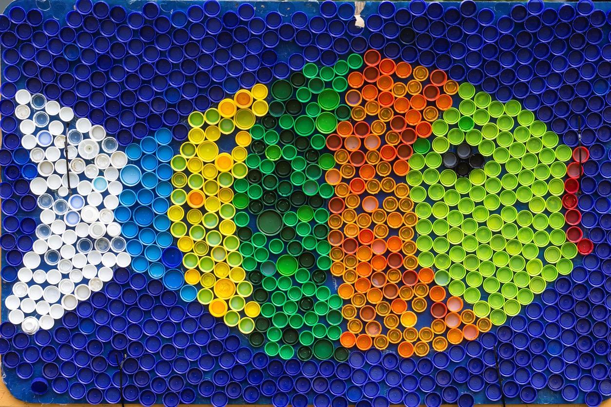 A large fish made out of different sizes and colors of plastic bottle caps.