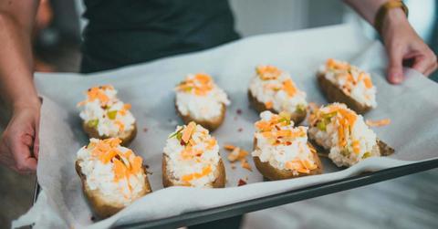 Man takes the baked potatoes with stuffing out of the oven. (Representative Cover Image Source: Pexels | Erik Mclean)