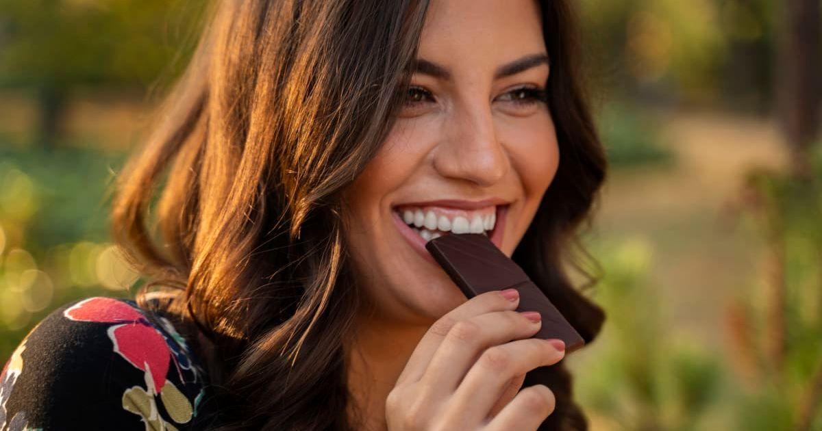 Woman happily eating dark chocolate in an outdoor setting (Representative Cover Image Source: Getty Images | Phoenixns)