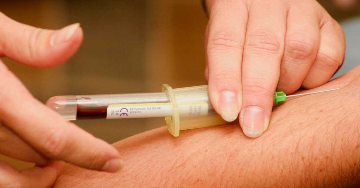 A closeup of a person taking someone else's blood as part of a blood test