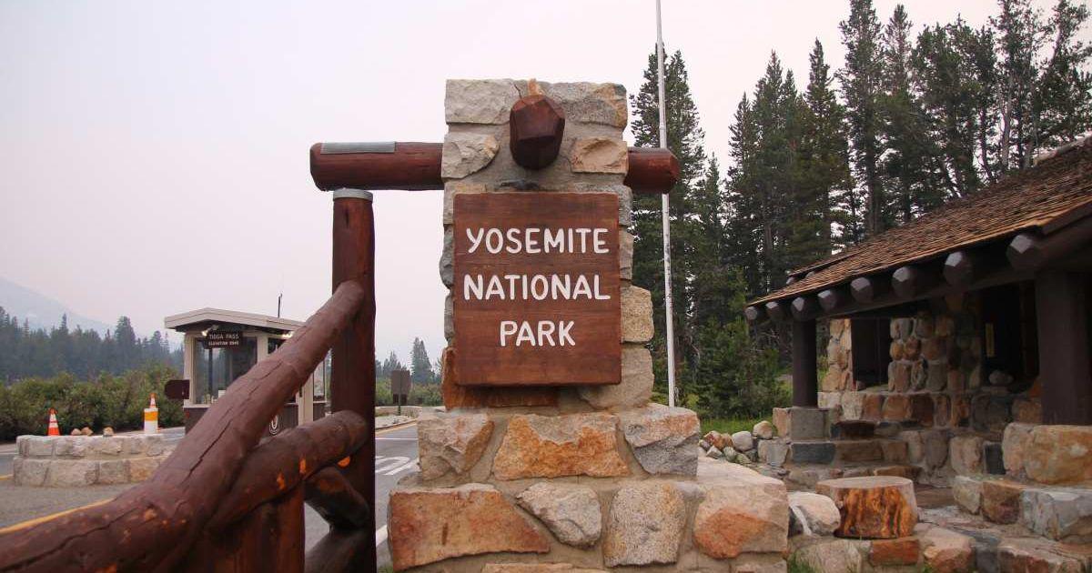 Yosemite National Park sign dangling on a brick structure in front of a hut (Representative Cover Image Source: Getty Images | WillEye)