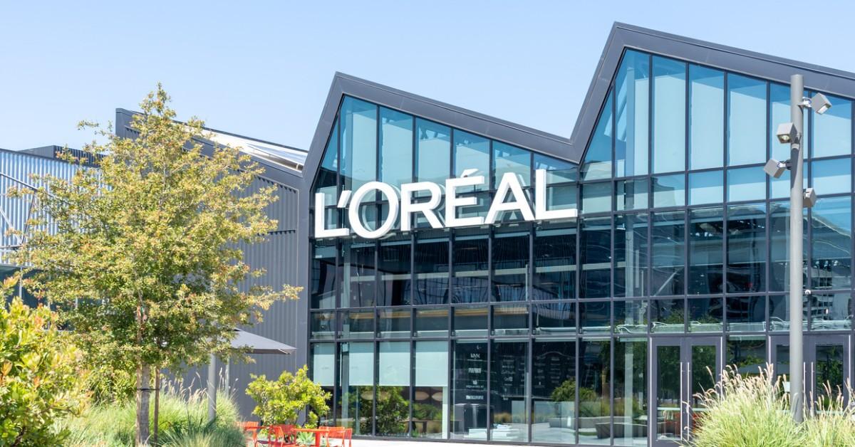 A sign hangs on a large glass-fronted building that reads L’Oréal