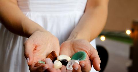 Hands holding multicolored crystals.