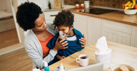 Black woman giving her son a nebulizer treatment at home