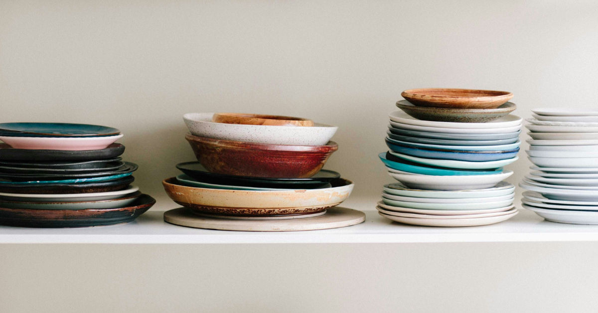 A stack of colorful plates sit atop a shelf