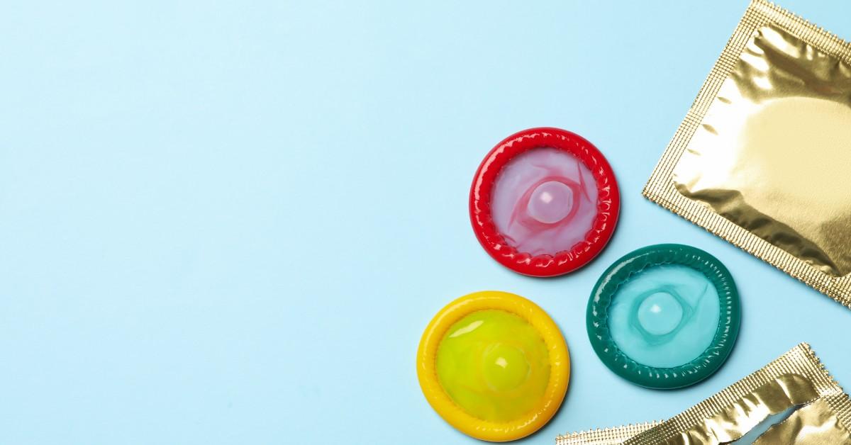 Red, yellow, and blue condoms next to gold foil wrappers