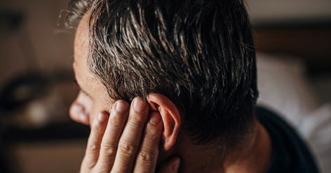 man with gray hair holding ear