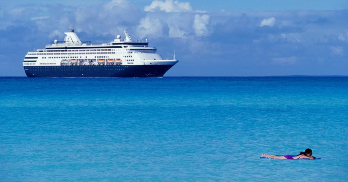 Woman swimming with a cruise ship in the distance