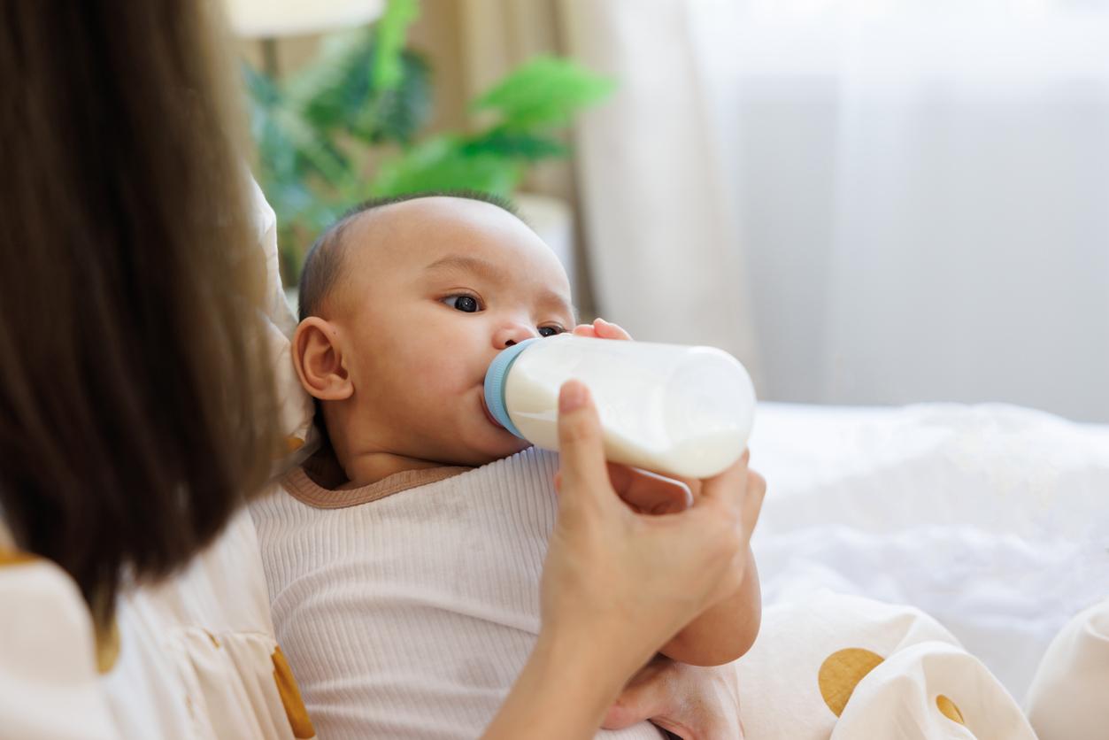 A mother feeds her child through a plastic milk bottle.