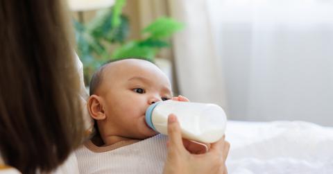 A mother feeds her child through a plastic milk bottle.