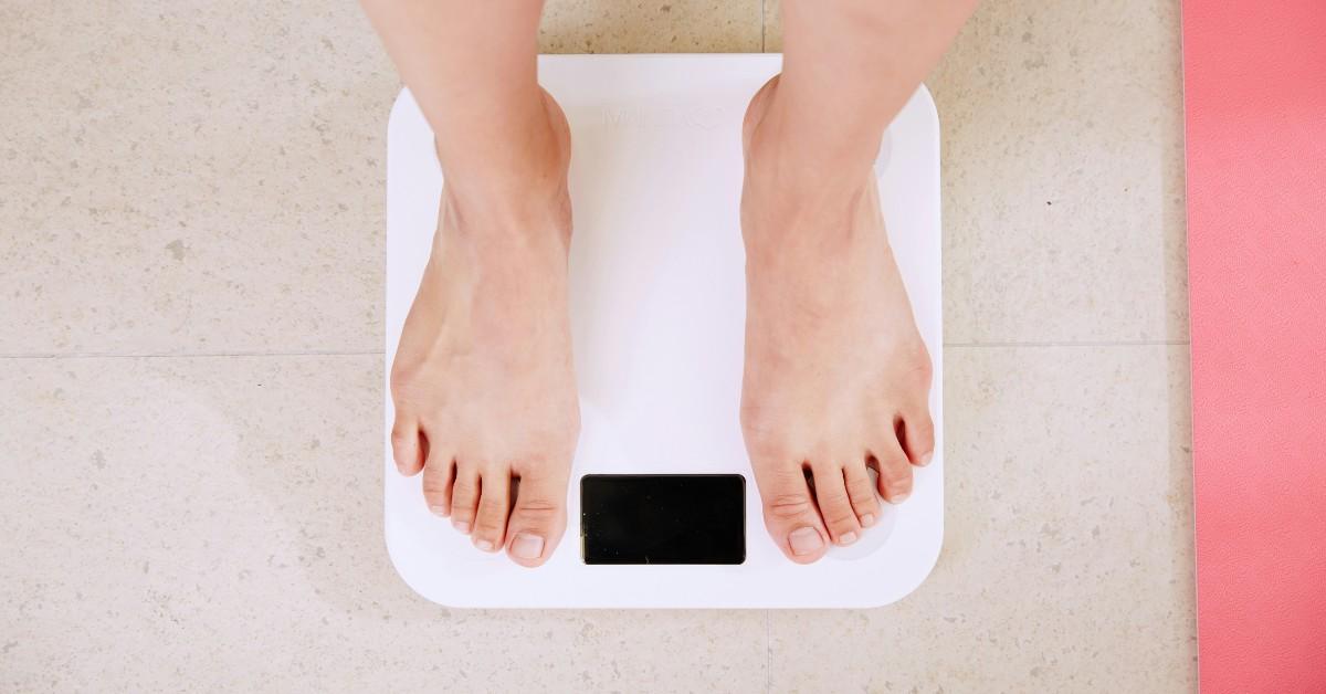 A woman stands on a white bathroom scale