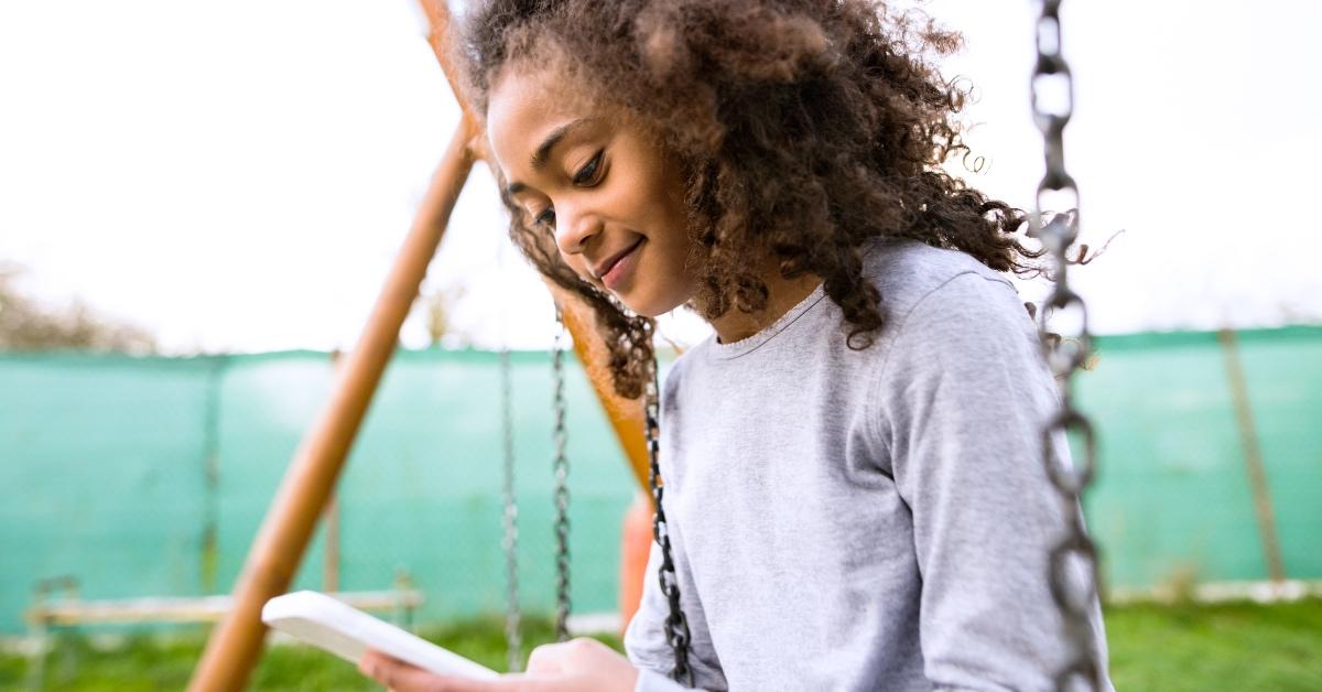 A young girl plays outside in long-sleeved, UPF protective clothing.