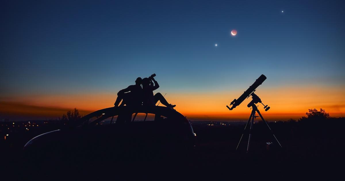 People look at planets in the night sky.