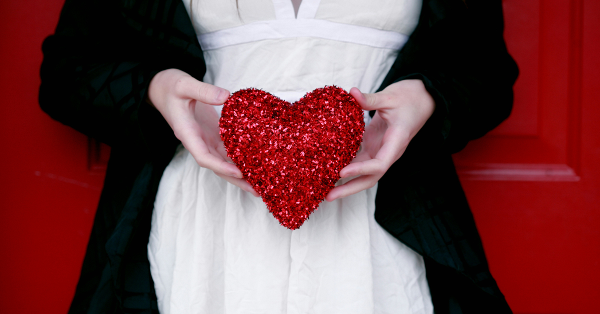 A woman in a white dress with a black jacket holds out a red sparkling star