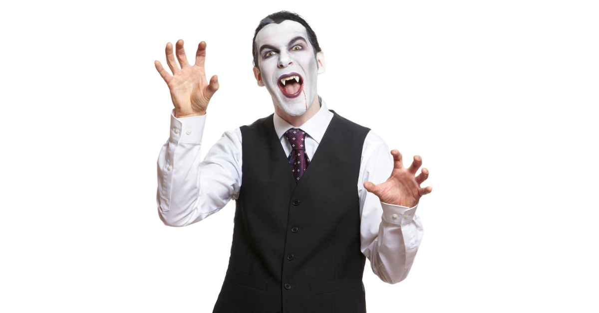 A man painted his face white while wearing a vest and tie to look like a vampire