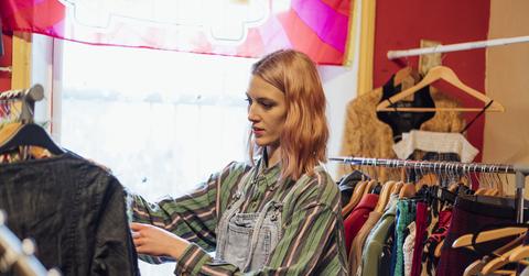 Woman shopping through racks of clothing at a thrift store