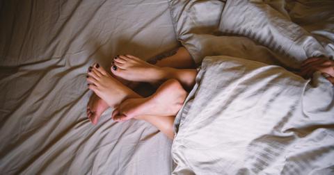Photo of two pairs of feet intertwined in a bed