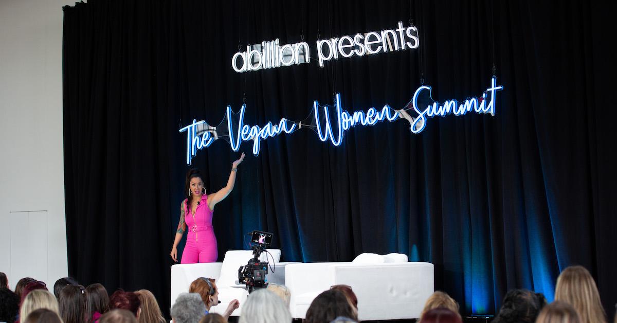 Jennifer Stojkovic, in a pink outfit, speaks on the Vegan Women Summit stage