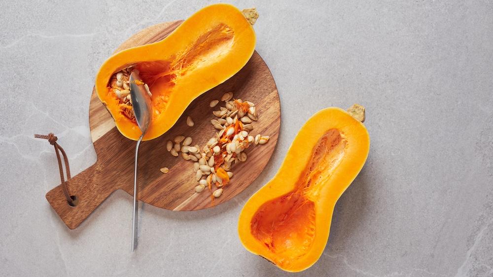 A butternut squash cut in half with the seeds scooped out.