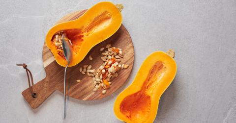 A butternut squash cut in half with the seeds scooped out.