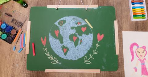 A chalk board with a drawing of the Earth sits on a table with other arts and crafts.