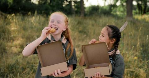 Two girl scouts enjoying a cookie from the boxes they were given to sell. (Representative Image Source: Pexels | Cottonbro Studios)