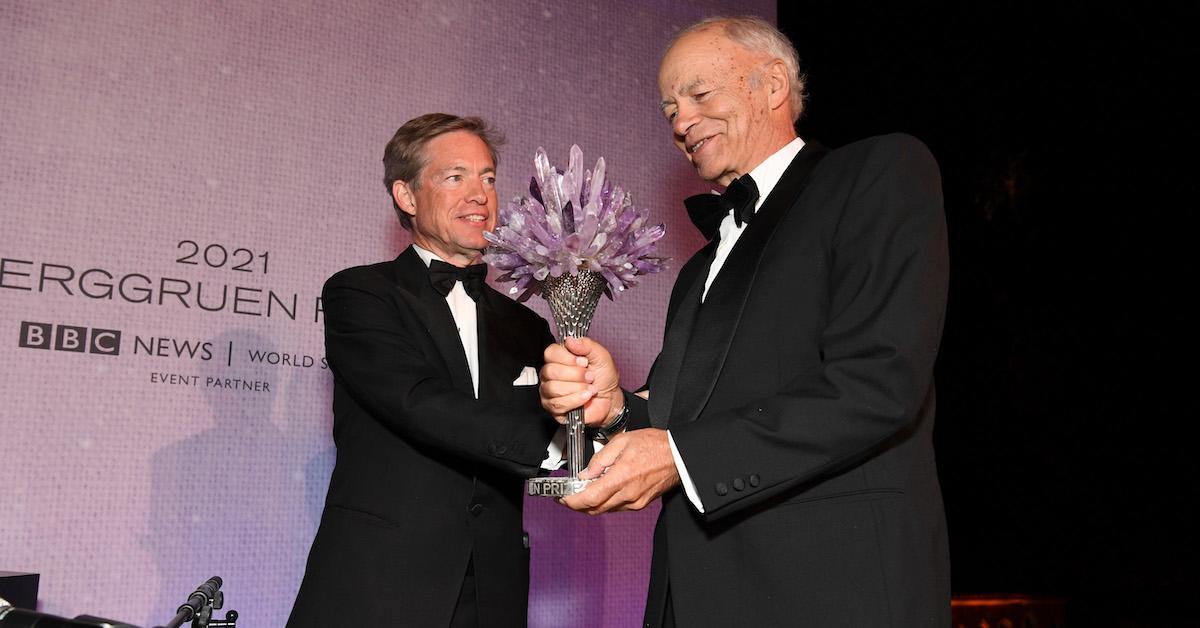 Nicolas Berggruen hands a bouquet of flowers to Peter Singer at an event.