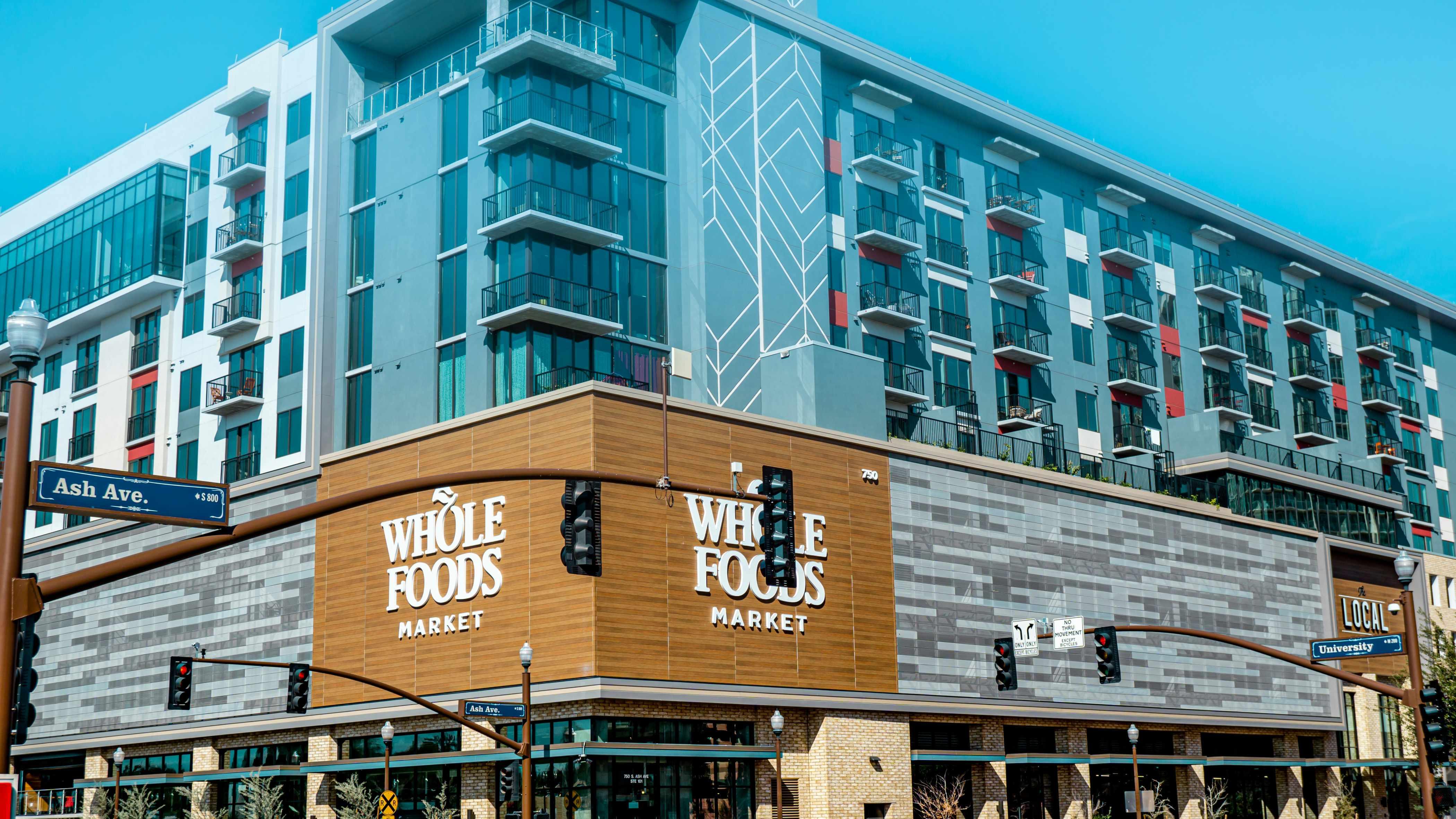 A Whole Foods Market building is pictured nestled in a city.