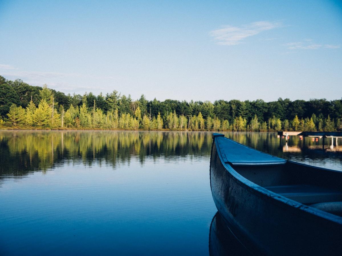 Canoe on a calm lake by a green forest