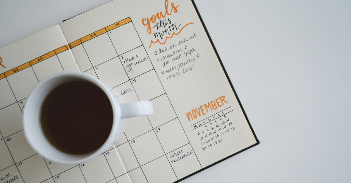 A cup of coffee sits in the middle of an open calendar