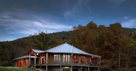 A Deltec Home sits on the side of a lake in the mountains.