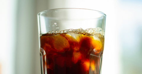 A fizzy glass of brown soda sits on a counter